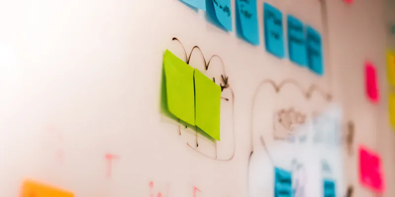 Whiteboard mit Haftnotizen und skizzierten Abläufen aus einem Prozess-Workshop