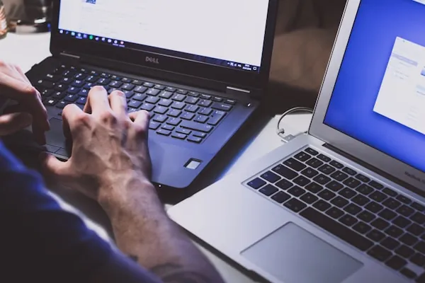 Hände tippen im Halbdunkel auf einem Laptop – Schatten-KI: unbemerkte KI-Nutzung mit Firmendaten am Arbeitsplatz