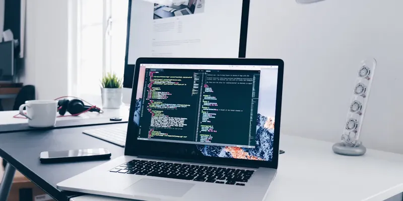 Laptop mit geöffnetem Programmcode auf einem hellen Schreibtisch