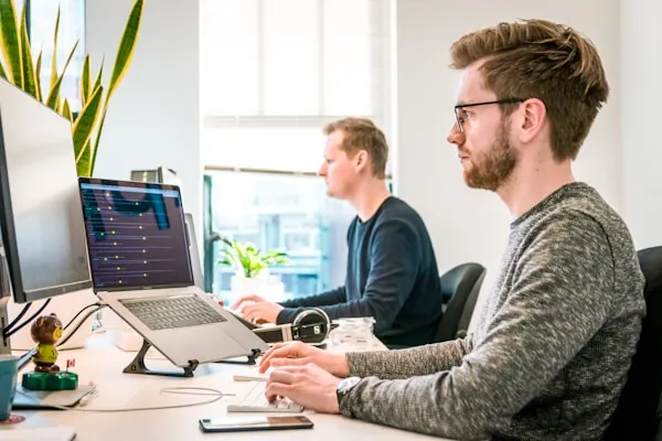 Zwei Mitarbeiter arbeiten im Büro an ihren Bildschirmen